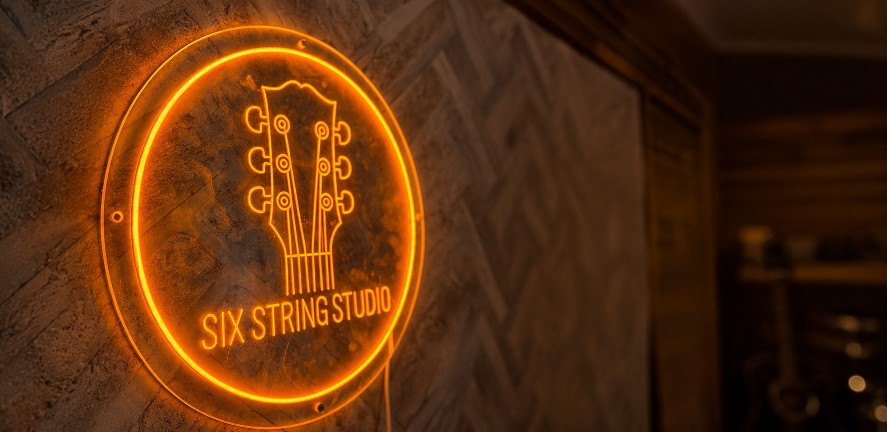 Orange Six String Studio neon sign on the studio wall